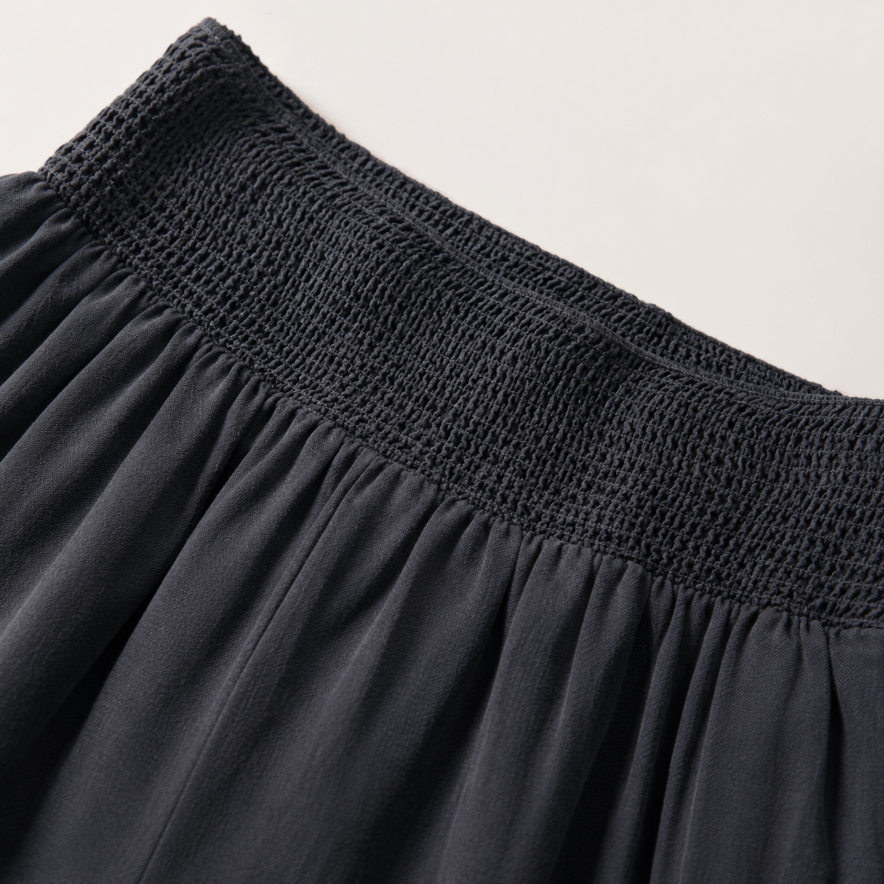 Close-up of a dark charcoal gray skirt showing the smocked elastic waistband and gathered fabric.
