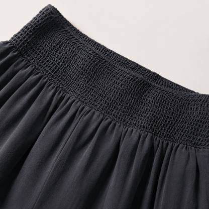 Close-up of a dark charcoal gray skirt showing the smocked elastic waistband and gathered fabric.